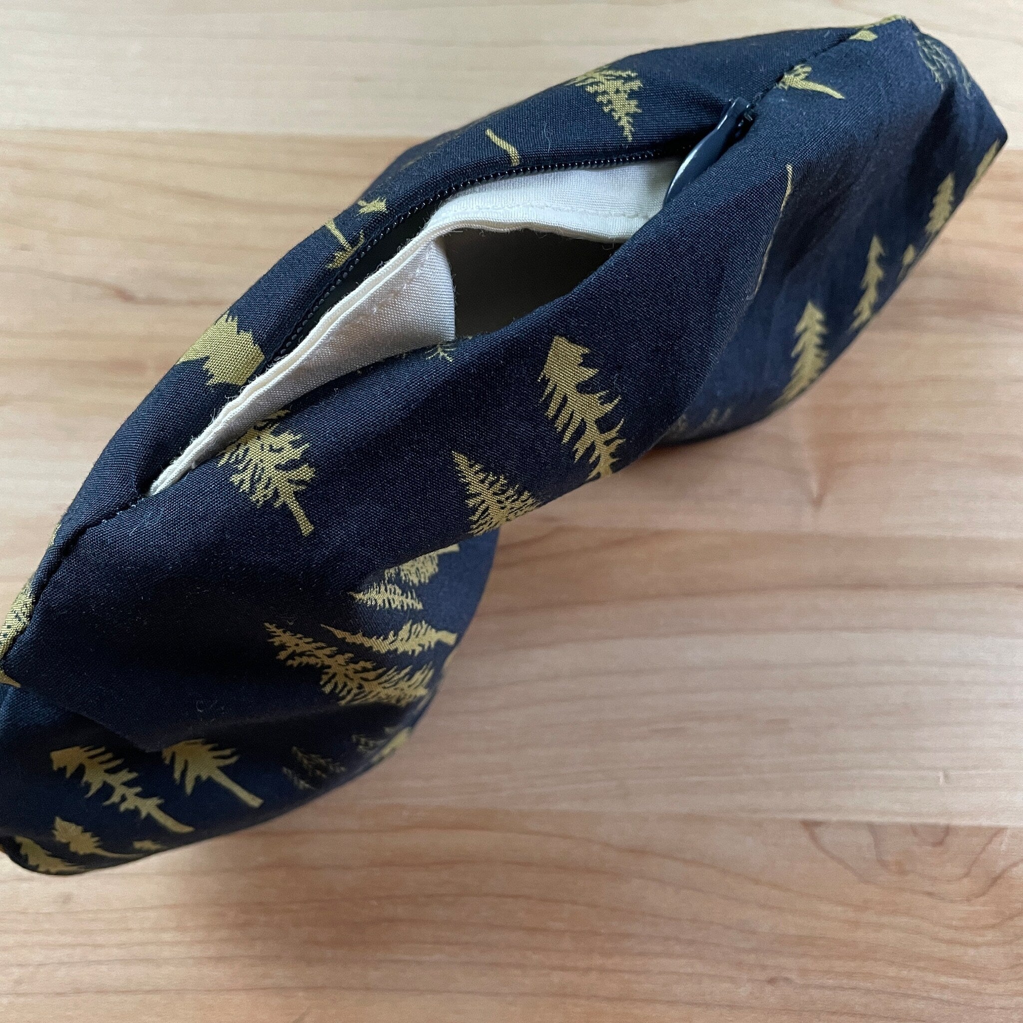 Pouch with navy fabric, gold tree pattern, and white interior with zipper closure