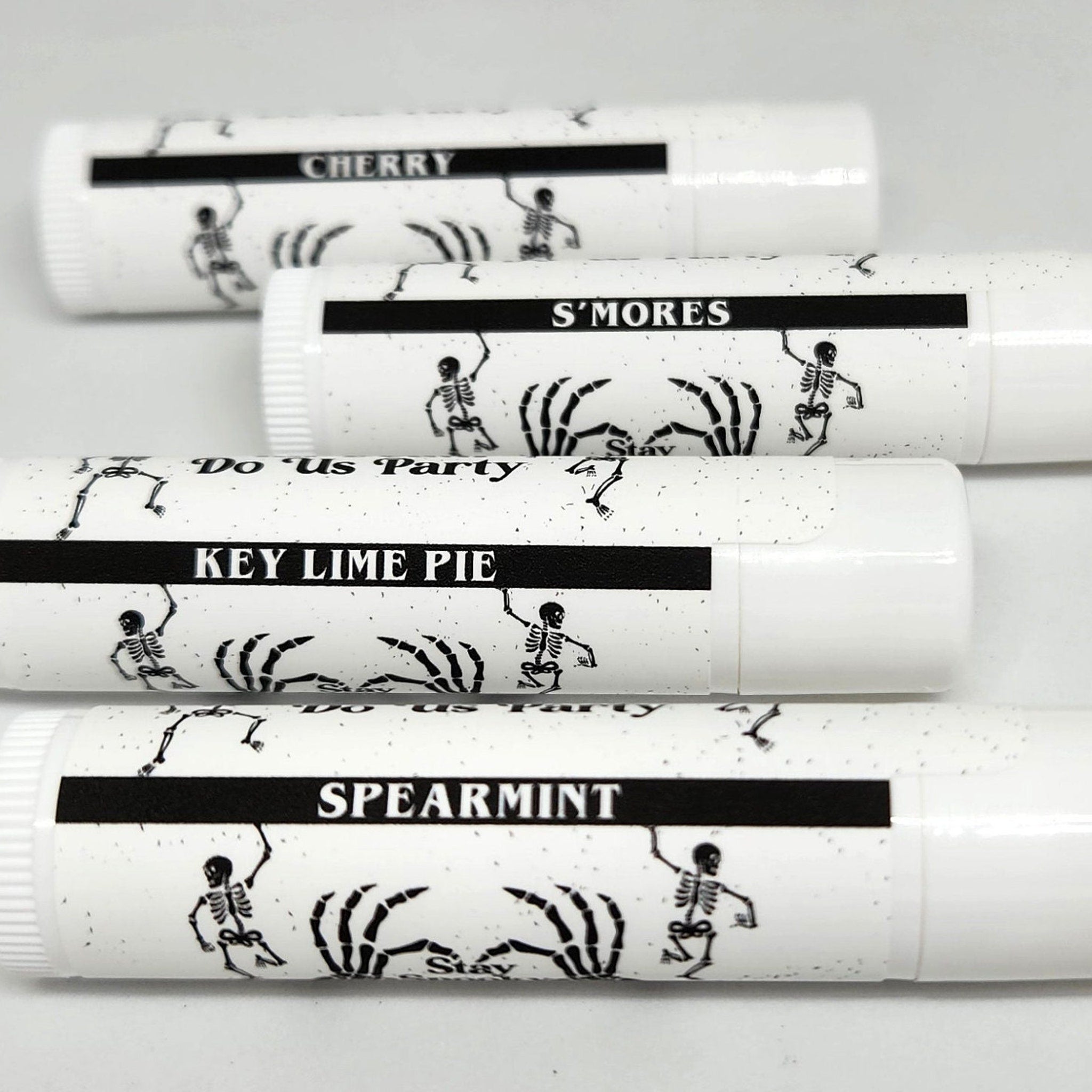 Lip balm tubes with white and black design, black text, and skeleton illustrations