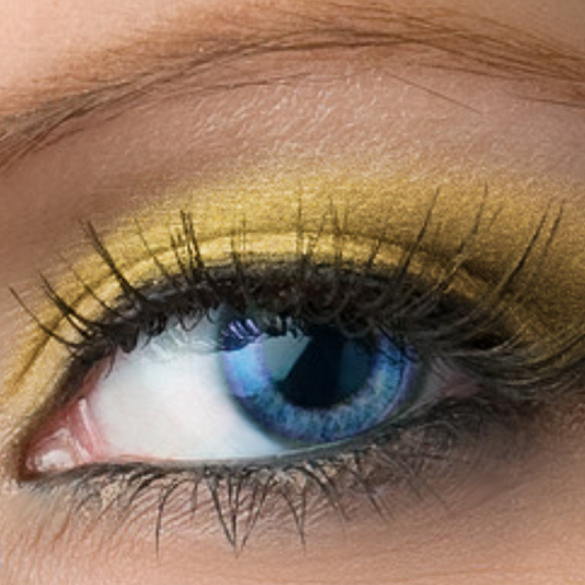 Eye makeup with gold eyeshadow, blue eye, and black eyelashes close-up