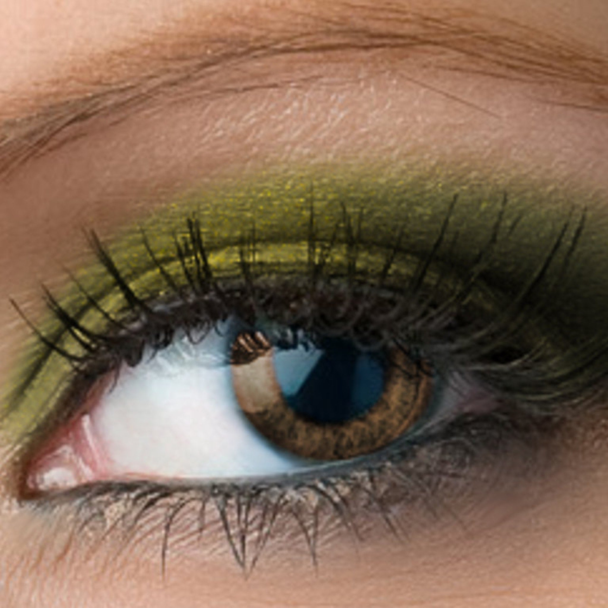 Eye makeup with green eyeshadow and black mascara, close-up of eye with brown iris