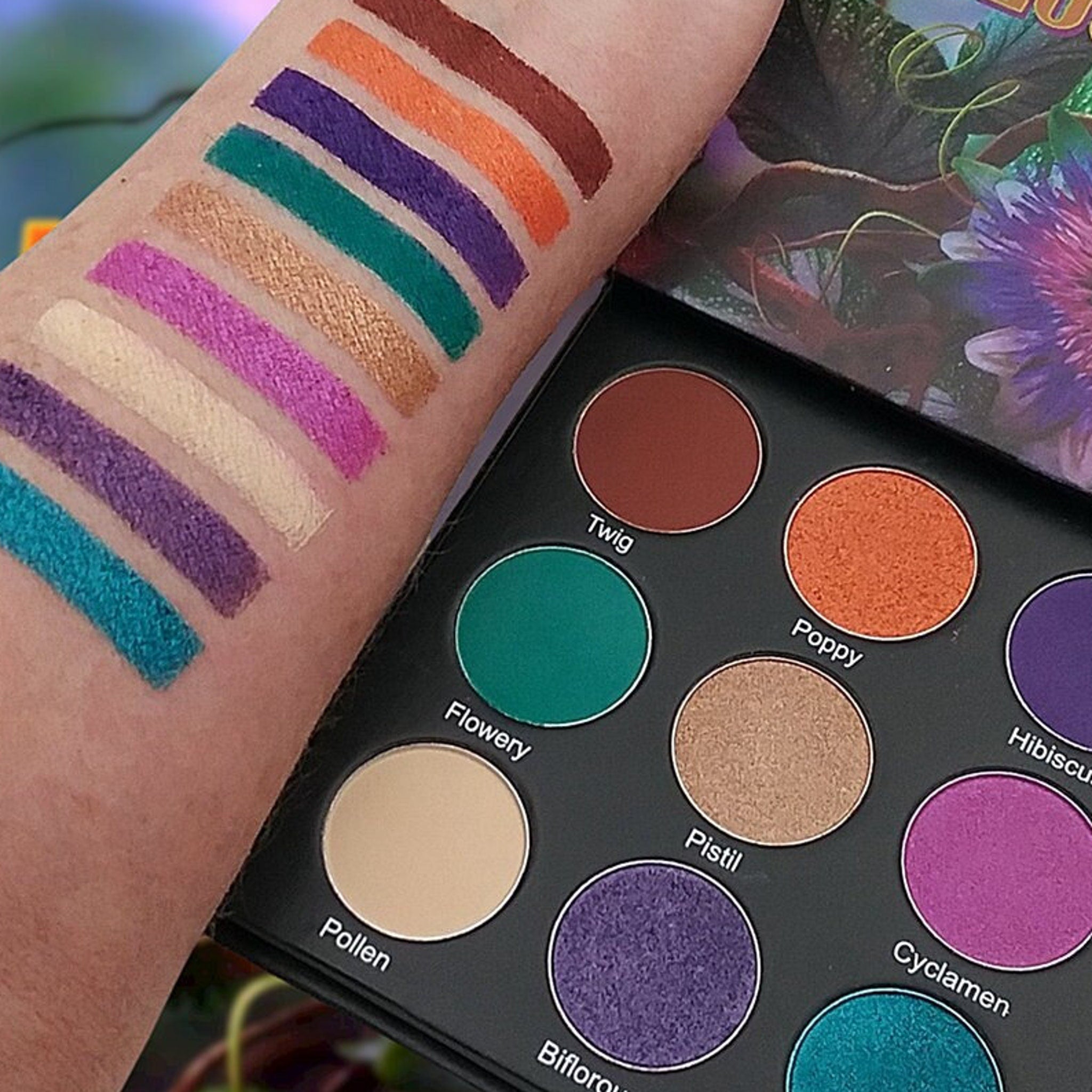 Eye shadow palette with colorful swatches on arm, and Abloom brand palette with round pans