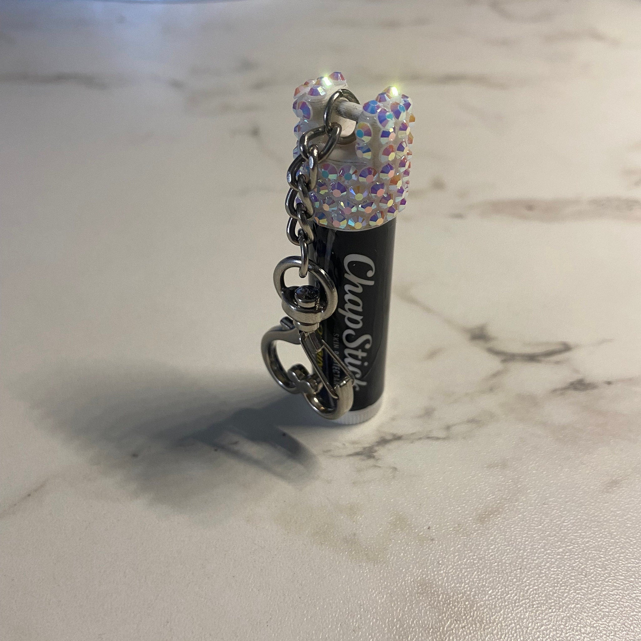 ChapStick with iridescent rhinestones, black tube, and silver chain keychain attachment