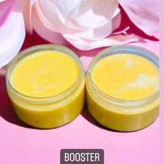 Booster cream in yellow color, clear glass jars, on pink background with flower petals