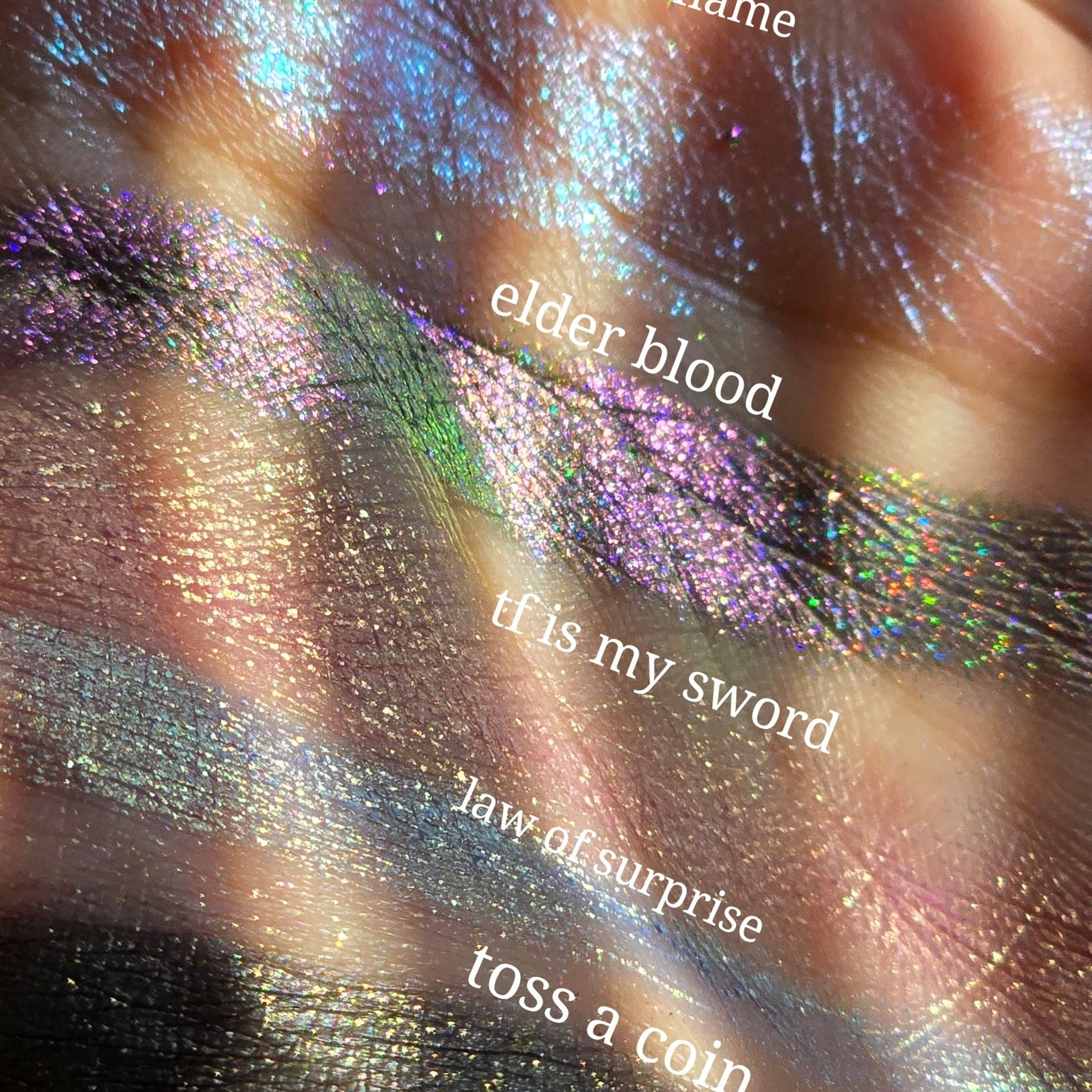 Side view of five multichrome pressed eyeshadows showing shimmery color shift from violet to green in angled lighting