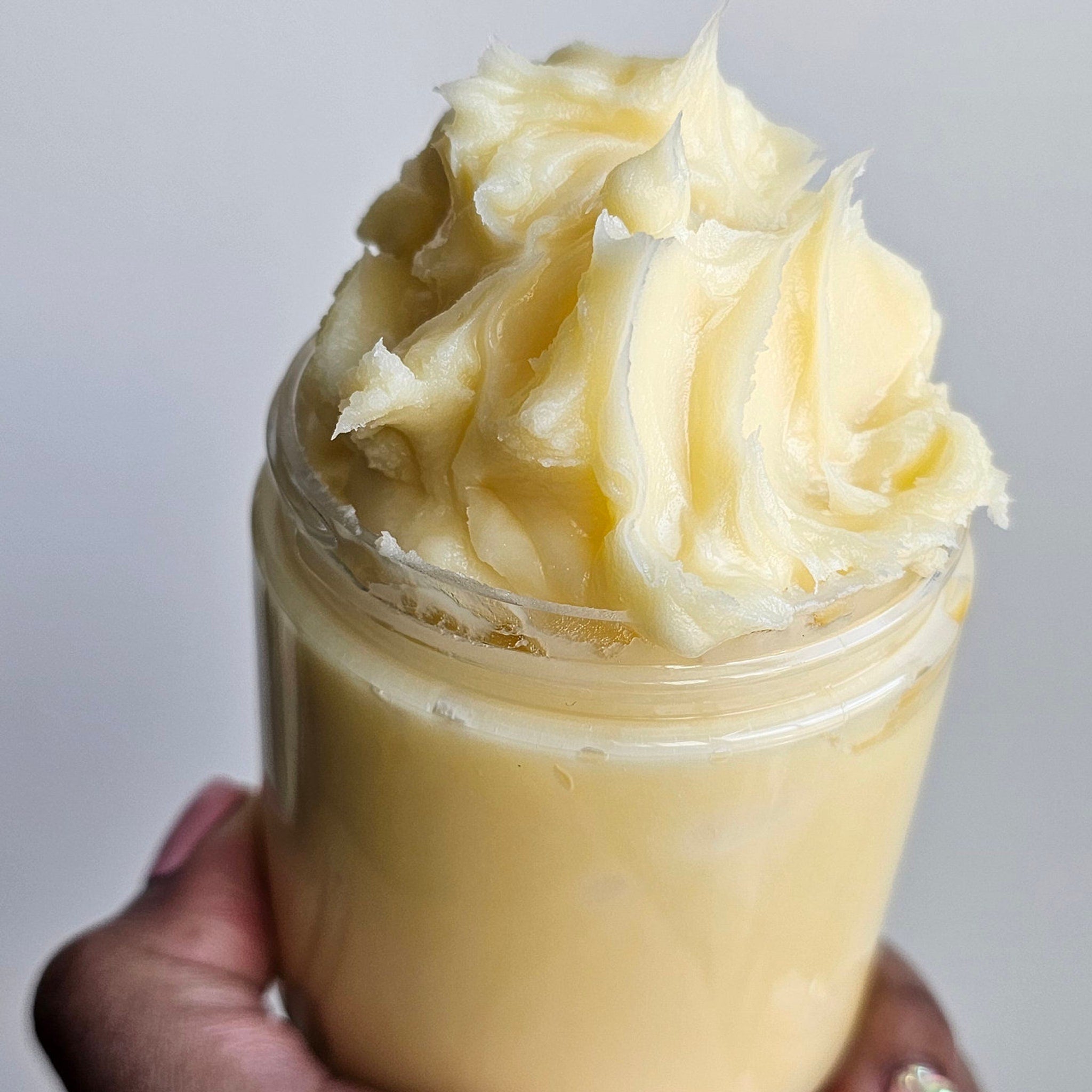 Golden argan butter in amber glass jar with minimalist label, shown at a 45-degree angle on marble surface