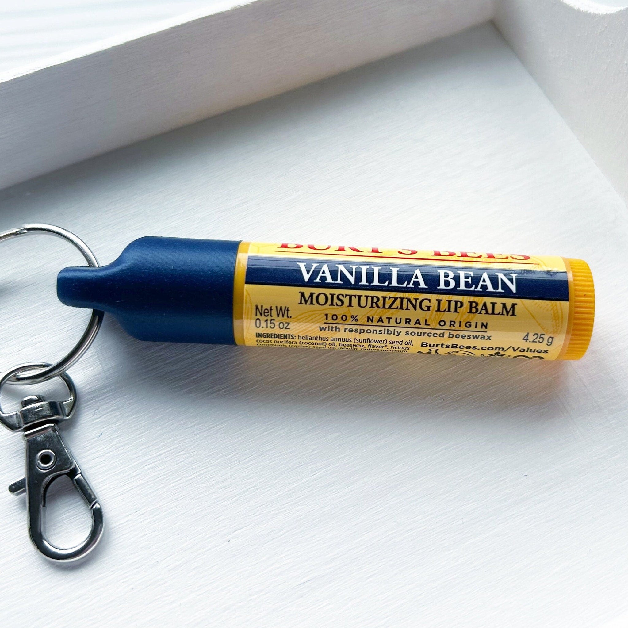 Lip balm tube with blue and yellow sections, Burt's Bees branding, and a silver keychain