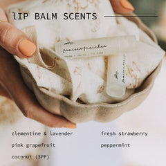 Lip balm tubes in clear and white with text, resting in a beige ceramic bowl, held by a person