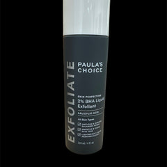 Exfoliant skincare product, dark gray bottle with white cap, Paula's Choice brand name visible