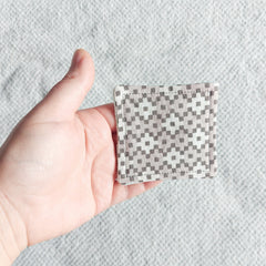 Square patterned fabric pad, gray and white geometric pattern, held in hand