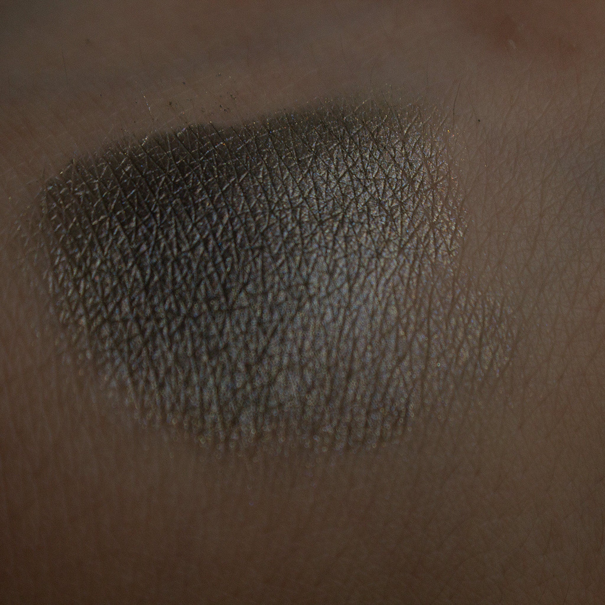 Square compact of vegan taupe shimmer eye shadow with mirrored lid and embossed logo, displayed open on marble surface