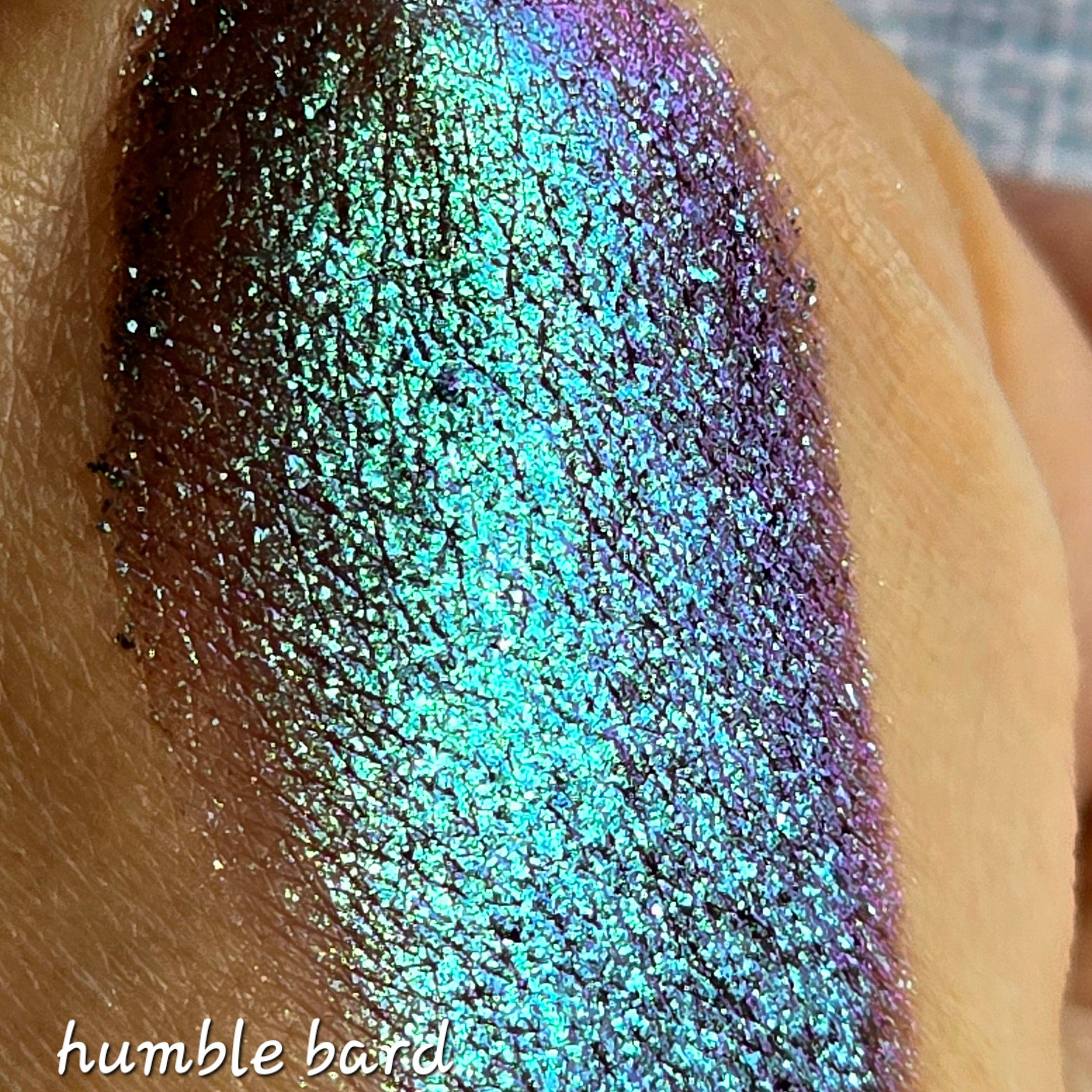 Close-up of shimmery multichrome eye shadow shifting between emerald green and sapphire blue hues in compact pan