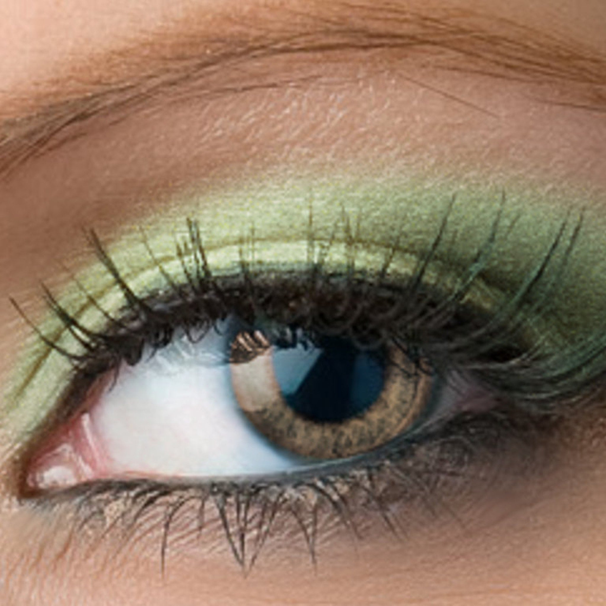 Side view of shimmery pistachio eyeshadow pan showing light spring green hue and reflective finish