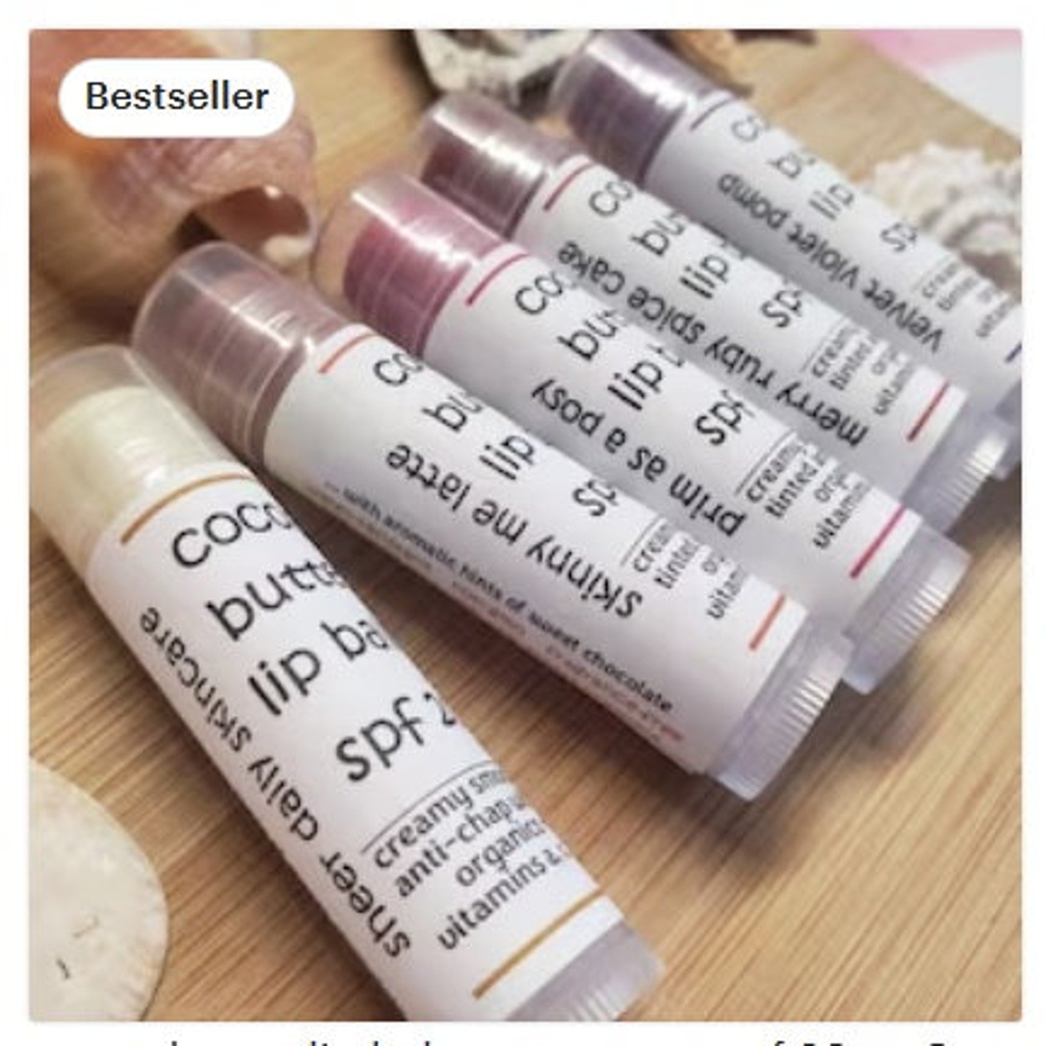 Lip balm tubes with white labels, various colors, and text labels on wooden surface