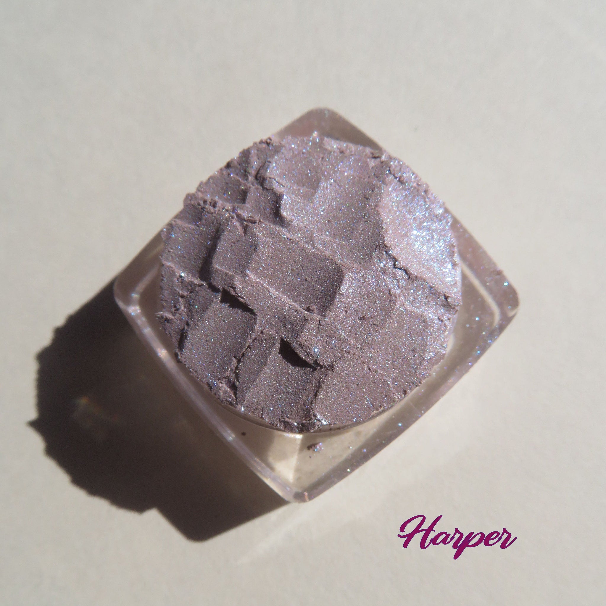 Close-up of three loose mineral eyeshadows in dark mauve matte and shimmering purple shades with vegan pigments
