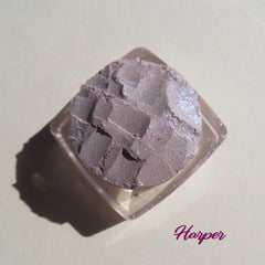 Close-up of three loose mineral eyeshadows in dark mauve matte and shimmering purple shades with vegan pigments