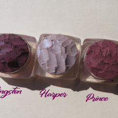Three vegan loose pigment eyeshadows in dark mauve matte and purple shimmer shades displayed in round jars