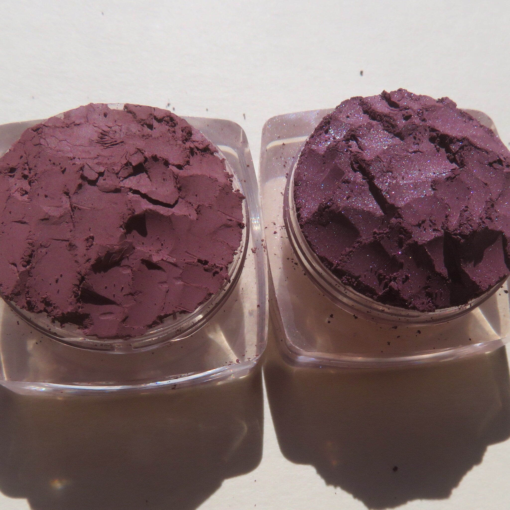 Side view of three purple shimmer loose pigment jars with dark mauve matte shade, showcasing mineral textures