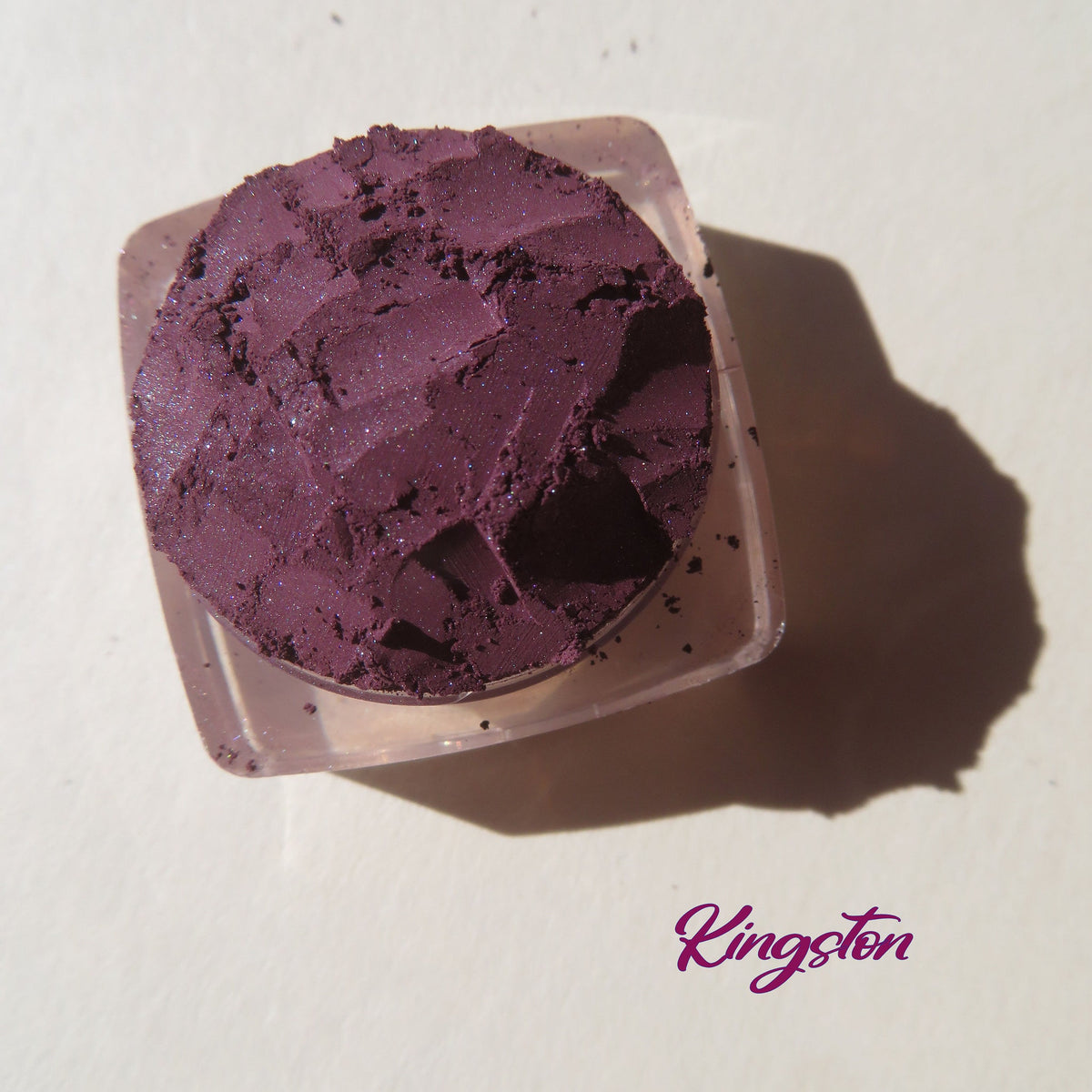 Close-up of dark purple shimmer vegan mineral eye shadow in loose powder form with eco-friendly packaging