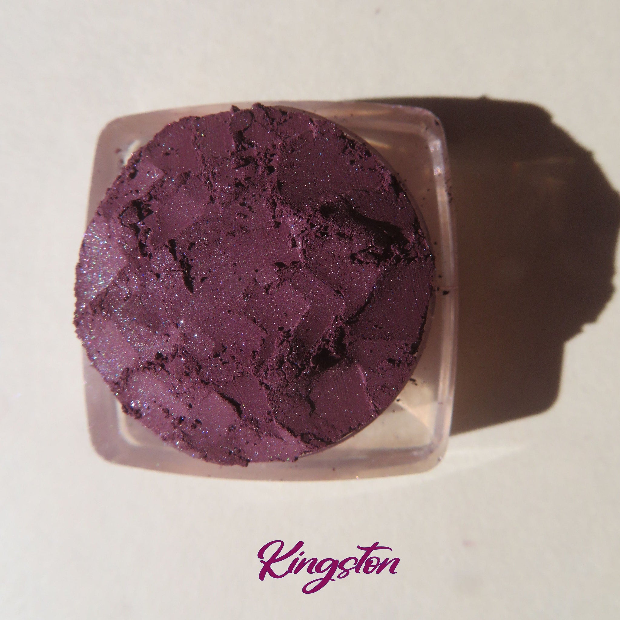 Side view of loose dark purple shimmer eye shadow powder in eco-friendly packaging with vegan mineral label