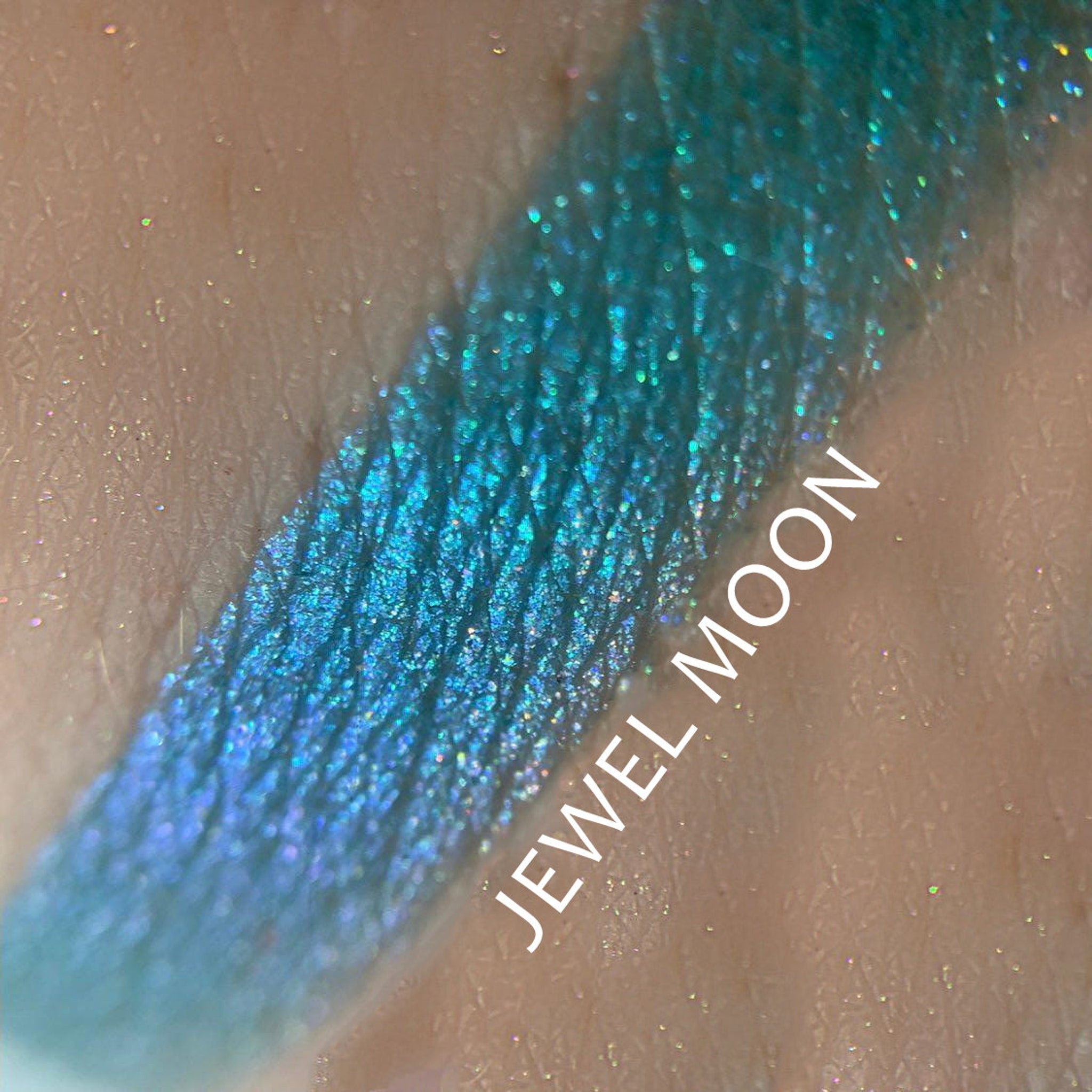 Side view of Jewel Moon Chrome Shifting Eyeshadow pot showing iridescent multi-color shimmer particles