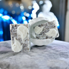 Soap bars with white flame design, speckled texture, and white ceramic dish on gray surface