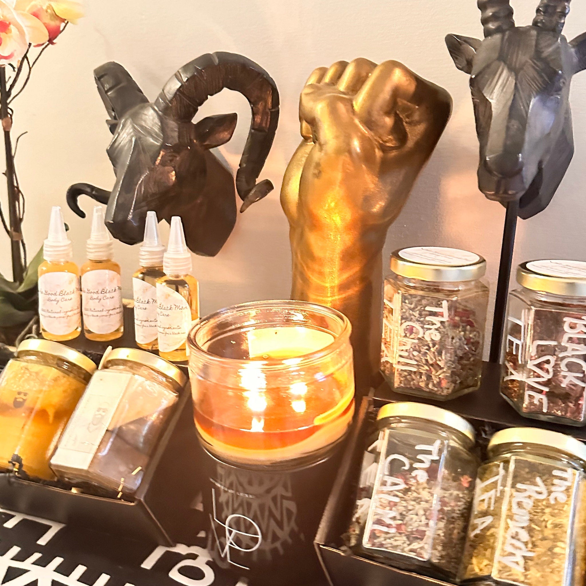 Body care products with clear glass bottles, "The Good Black Man" label, and amber liquid inside, displayed on a shelf