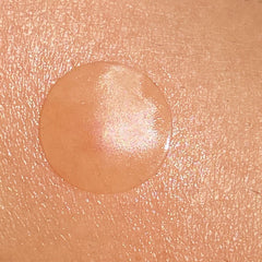 Skin serum droplet on skin, clear, peach-toned, shiny texture, close-up view