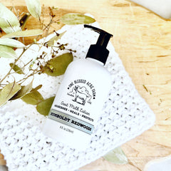 Goat milk lotion bottle with black pump, white label, and white crochet blanket on wood surface