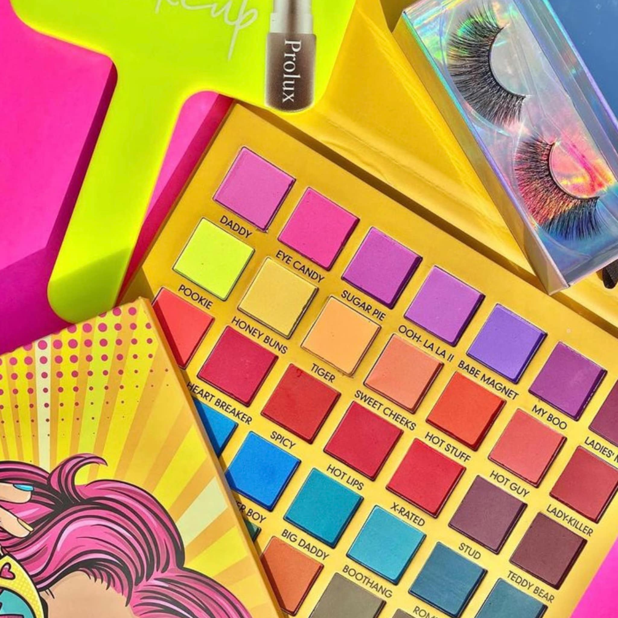 Eyeshadow palette with yellow, pink, and red shades, and a Prolux bottle, and a pair of false eyelashes