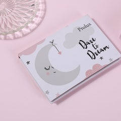 ProLux book with pink and gray illustrations, "Dare to Dream" text, and a moon design on pink background