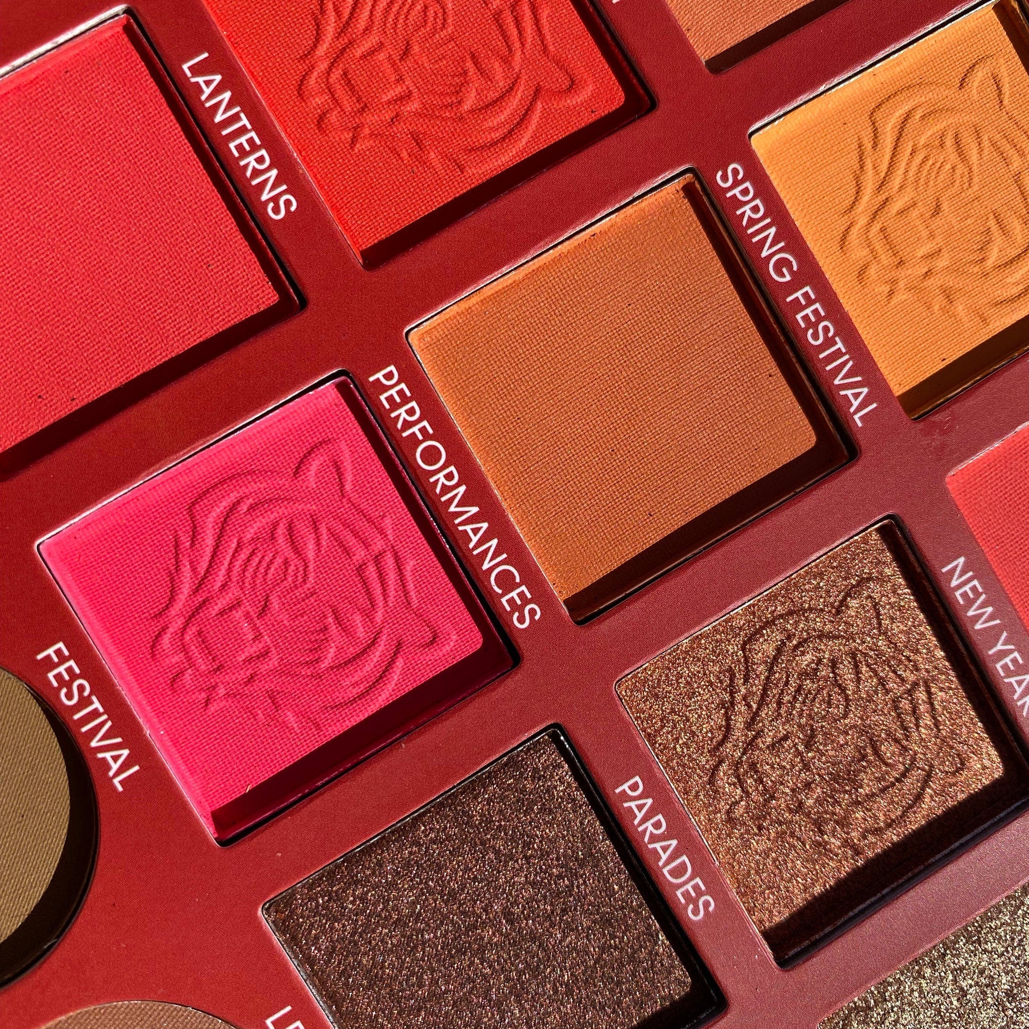 Eyeshadow palette with red, orange, and brown shades, textured surface, and embossed design