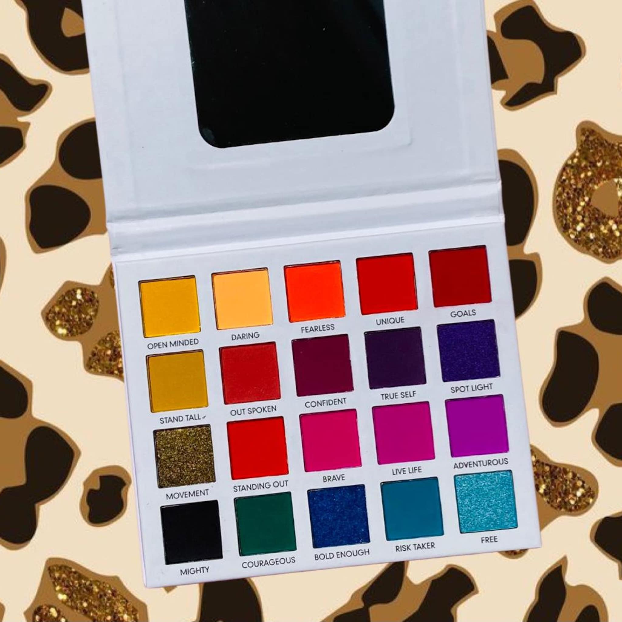 Eyeshadow palette with multiple colors, square pans, and a white compact for makeup application.