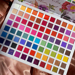 Eyeshadow palette with multiple colors, square pans, and floral design on the cover