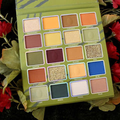 Eyeshadow palette with multiple colors, including orange, green, and blue, in a rectangular case with names on each shade.