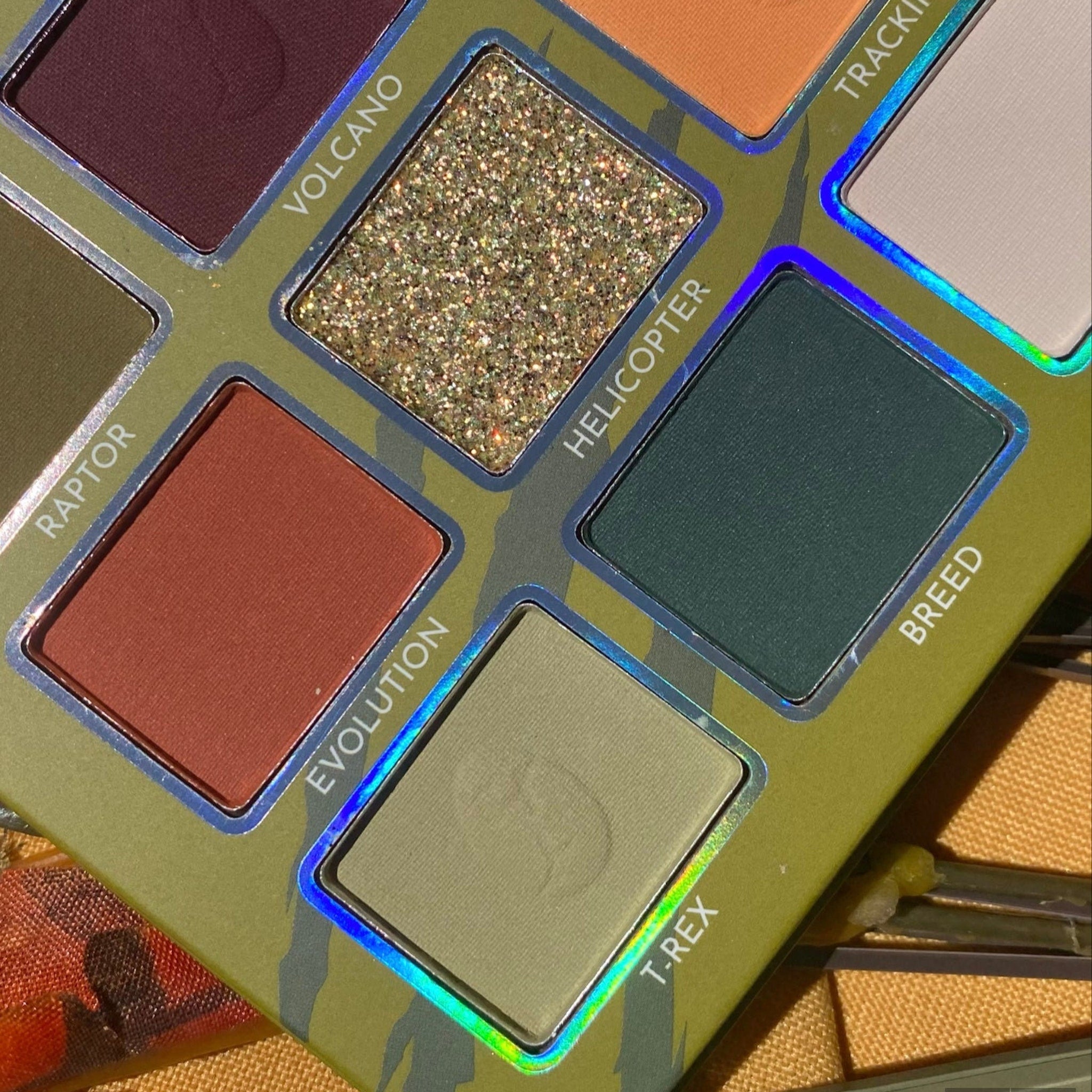 Eyeshadow palette with green, gold, and brown colors in a square design, for eye makeup