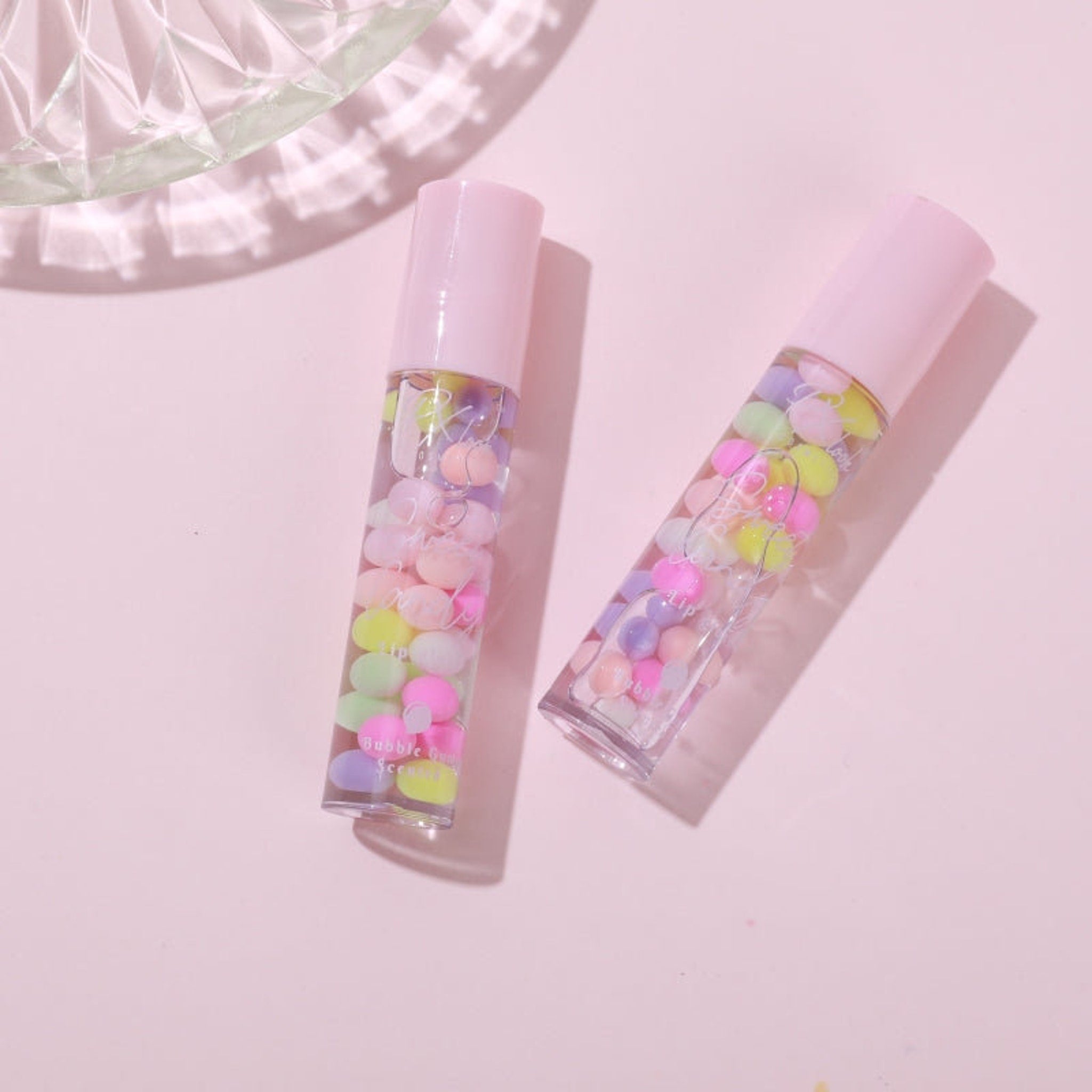 Side view of Sweet Candy Lip Gloss tube showcasing its glossy pink cap and transparent shimmer-filled formula