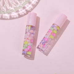 Side view of Sweet Candy Lip Gloss tube showcasing its glossy pink cap and transparent shimmer-filled formula