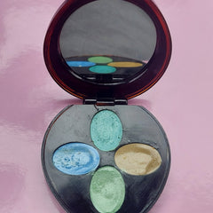 Eyeshadow compact with mirror, brown frame, black base with blue, green, and gold colors