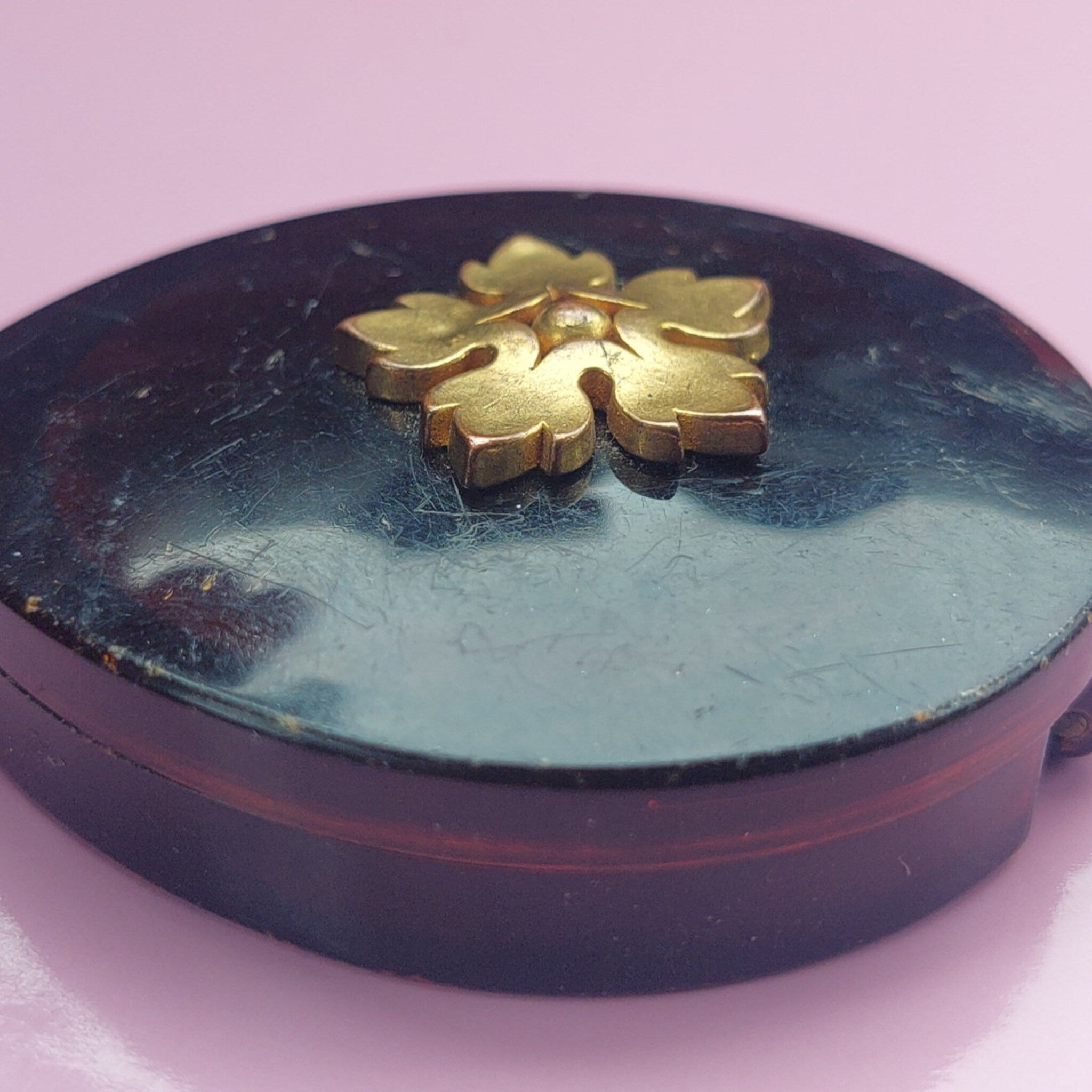 Vintage 1970s Avon eyeshadow compact with sparkling cream formula and flip-top mirror, displayed open on textured surface