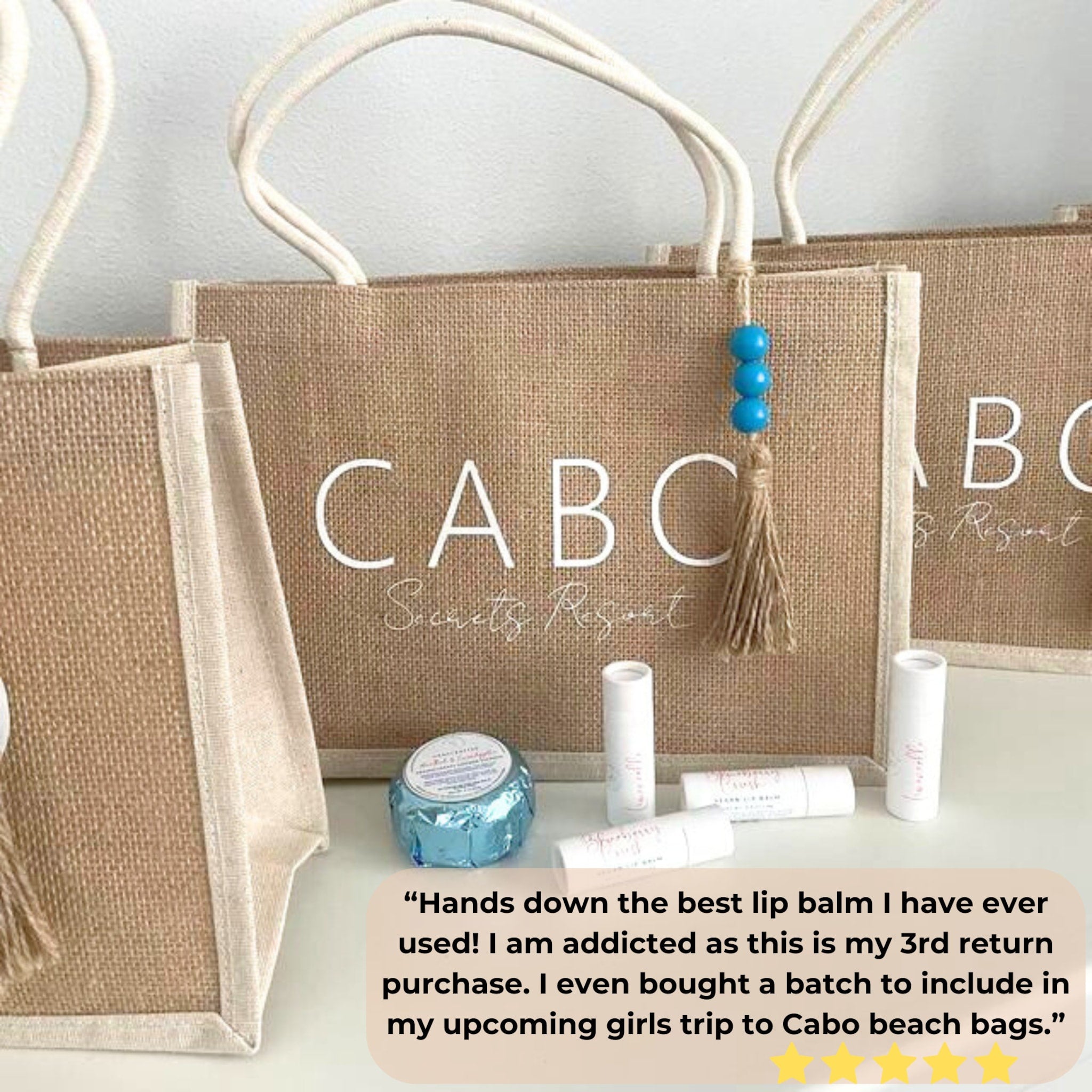 Jute tote bags with white text and cream handles, with lip balm and blue beads