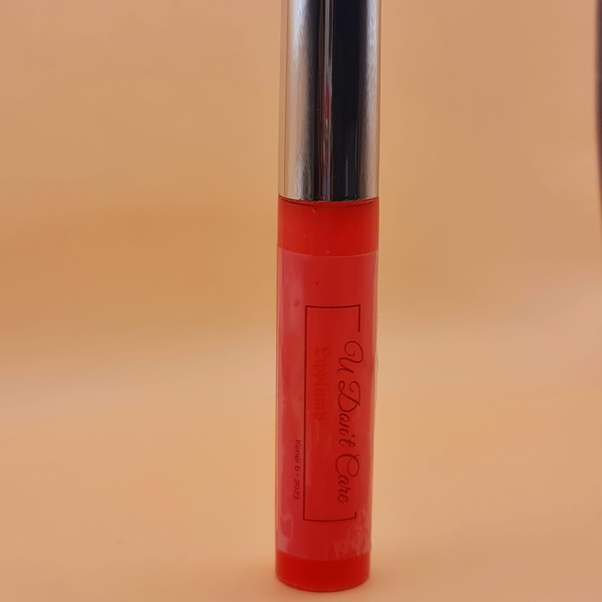 Lip gloss tube with red body, silver cap, and "U Don't Care" text label