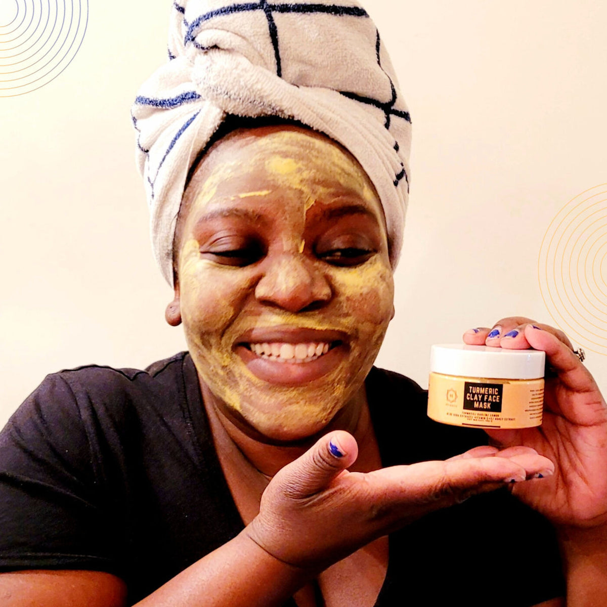 Golden turmeric clay mask in a sleek black jar with minimalist label, showcasing rich creamy texture