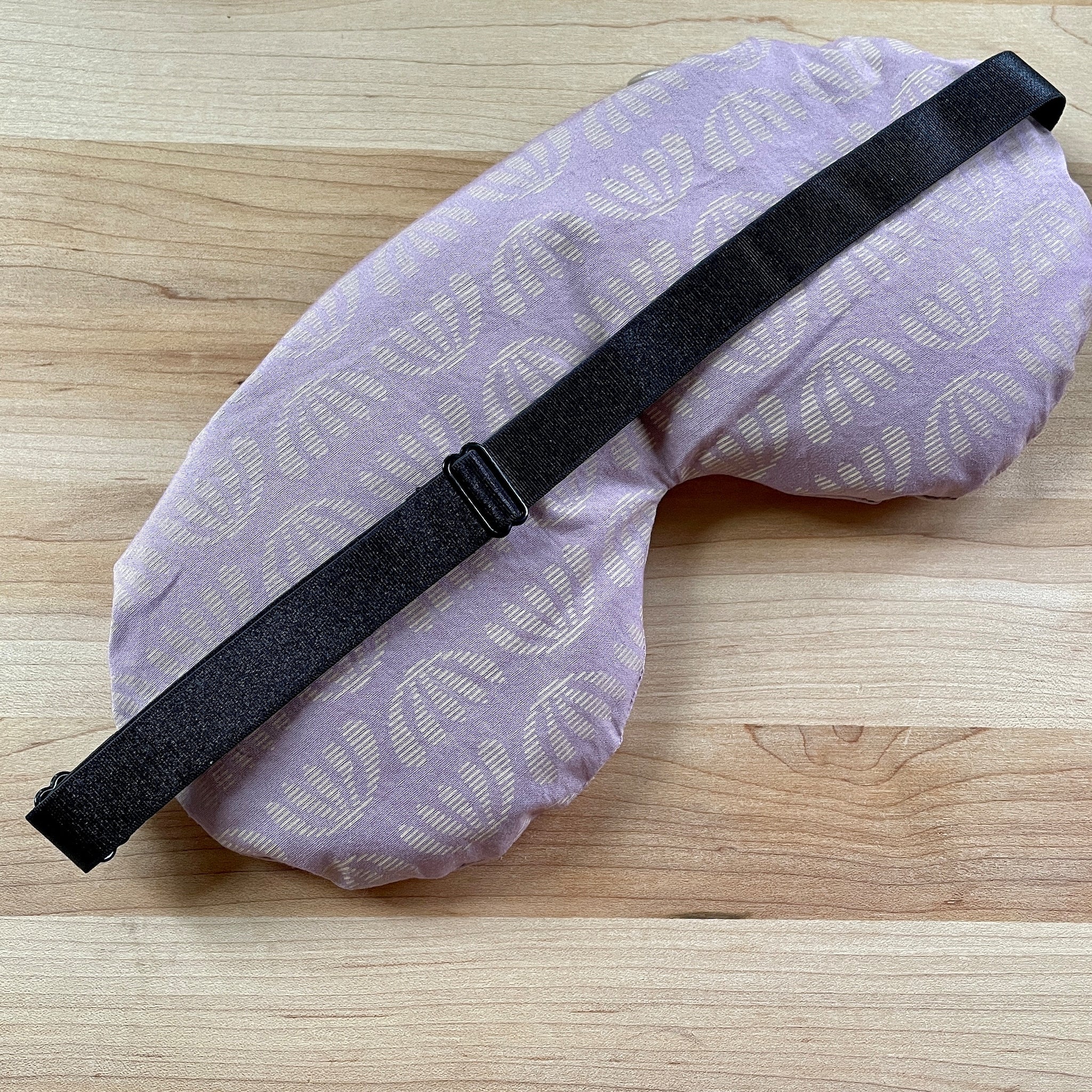 Sleep mask with lavender floral pattern, black strap, and soft fabric material
