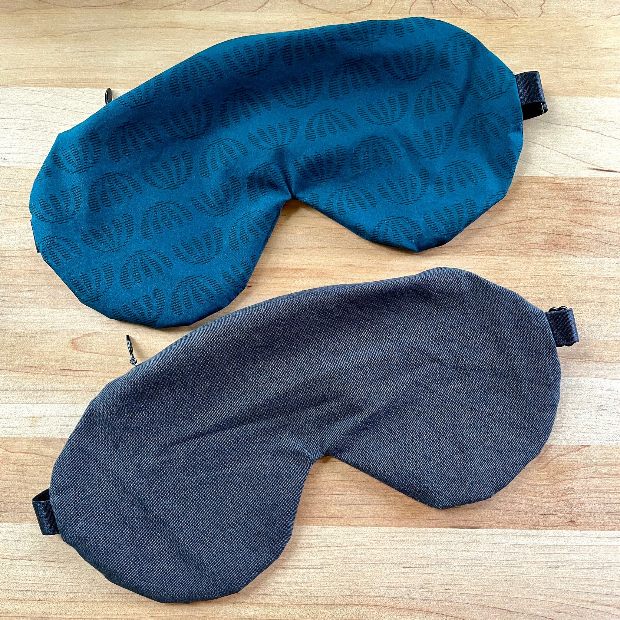 Sleep masks in teal patterned fabric and dark gray denim-like material, eye covering style