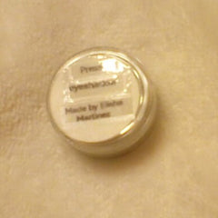 Close-up of a makeup brush applying pressed powder eye shadow in a shimmering bronze shade to eyelid.