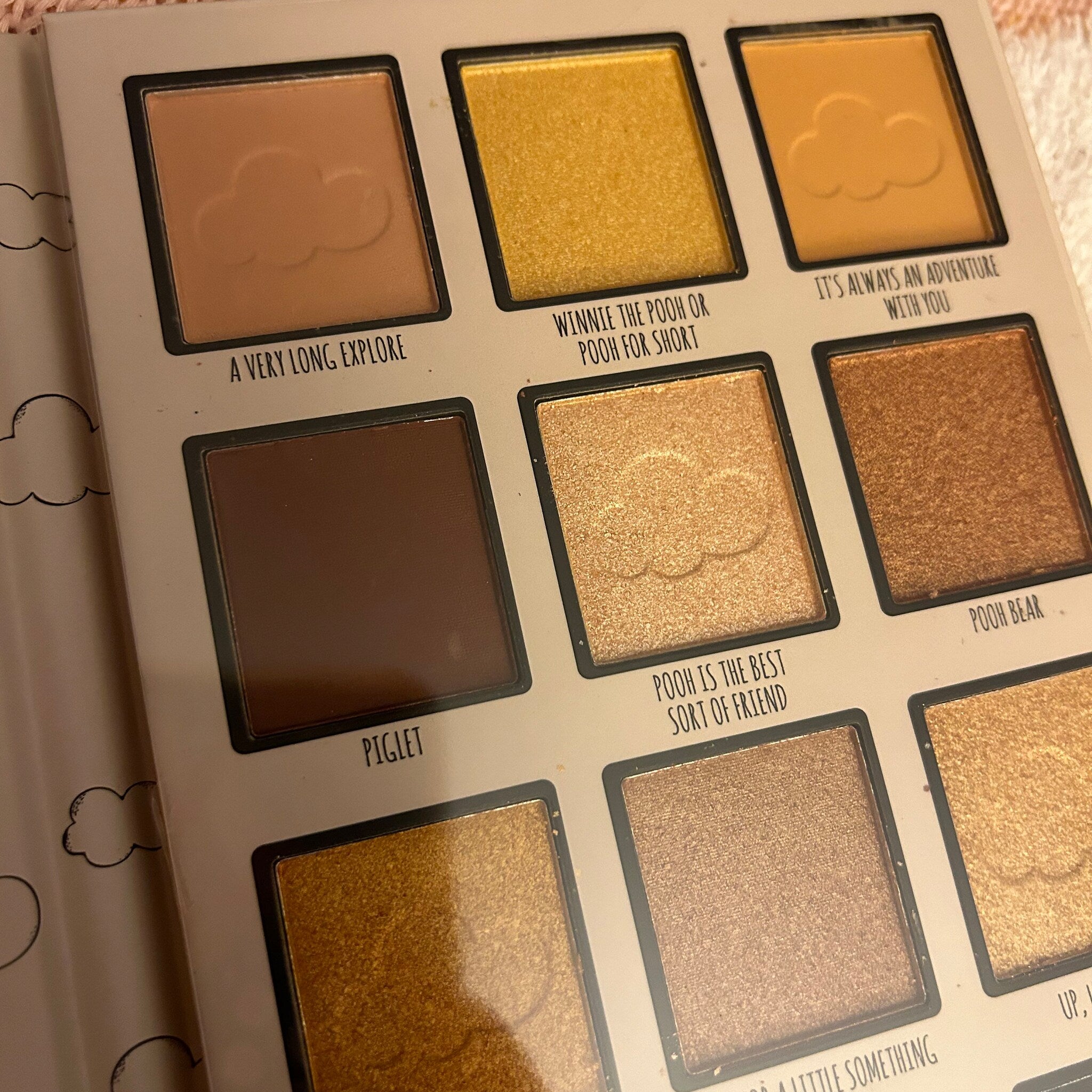 Close-up of makeup brush applying shimmering honey gold eyeshadow from Winnie the Pooh palette on eyelid