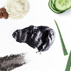 Black charcoal mask with white specks, green aloe vera, and cucumber slices on white background