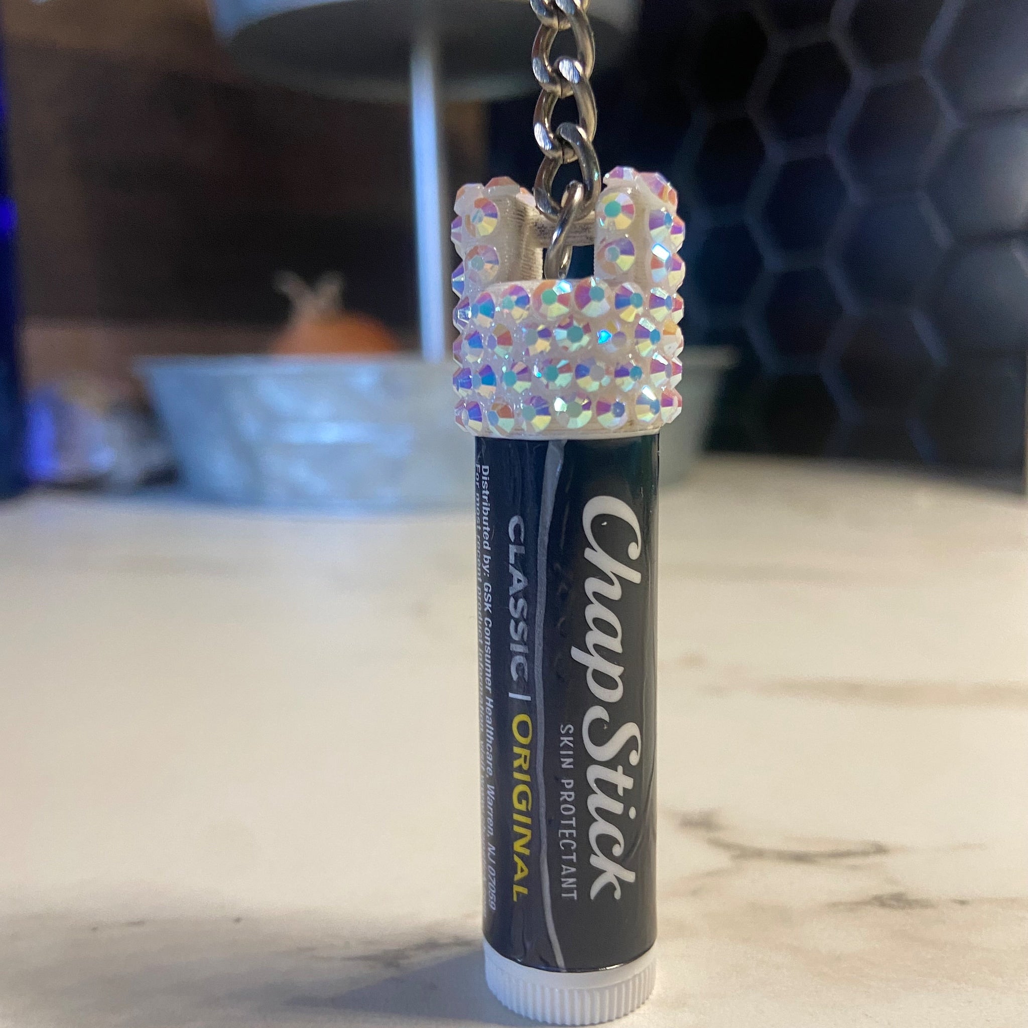 Chapstick cap keychain with iridescent rhinestone embellishments and silver chain, holding ChapStick tube