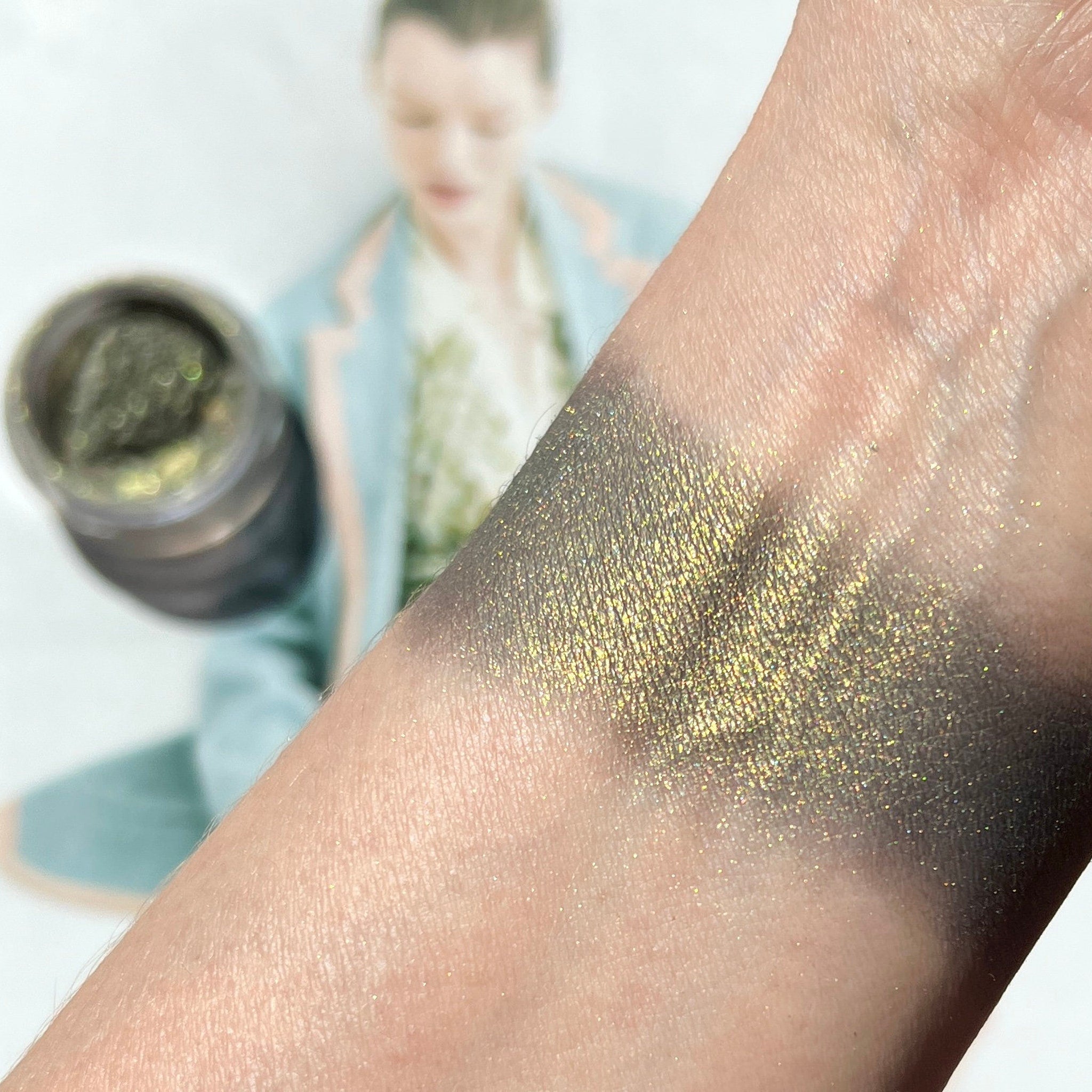 Close-up of mint green shimmer mineral eyeshadow with soft reflective particles in compact pan