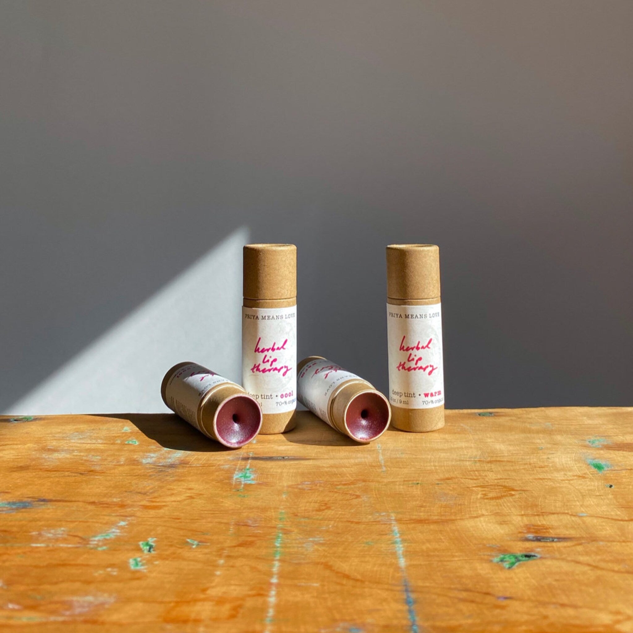 Lip therapy tubes in brown cardboard with white labels and red text on wooden surface